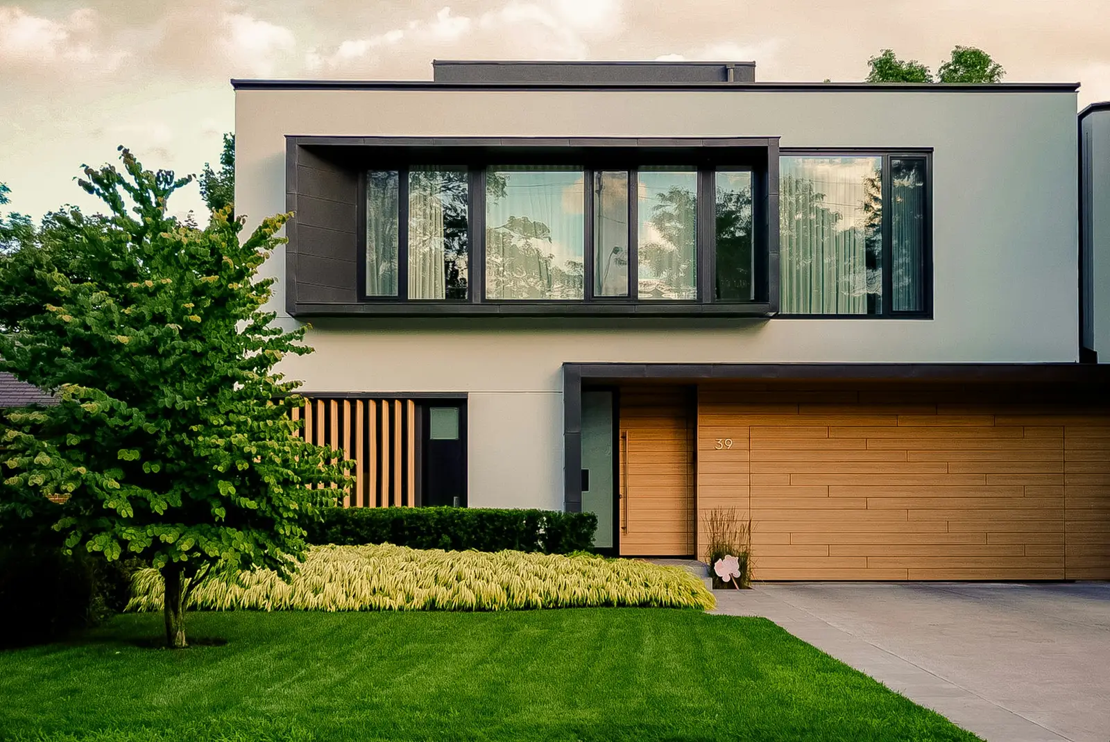 Two-story contemporary house with wood garage doors and a front yard
