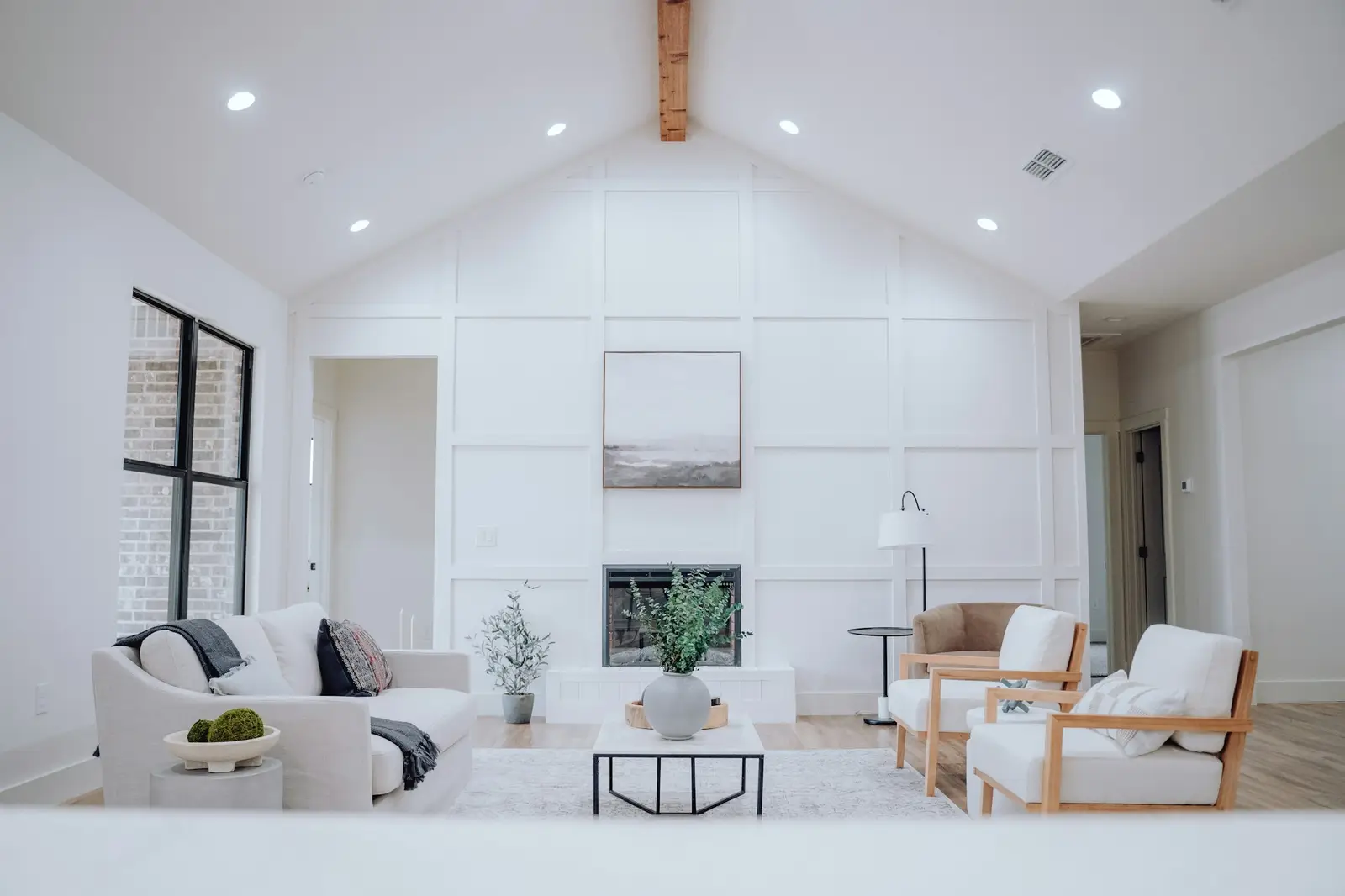 High-ceilinged living room with white paneling and exposed beams
