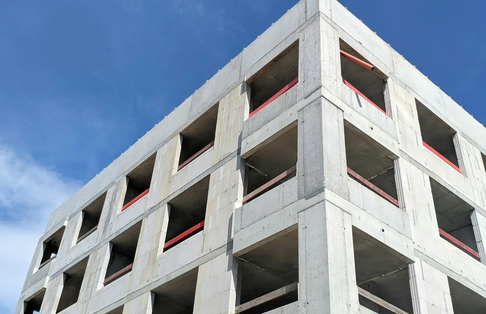Concrete frame building with open window openings under a blue sky