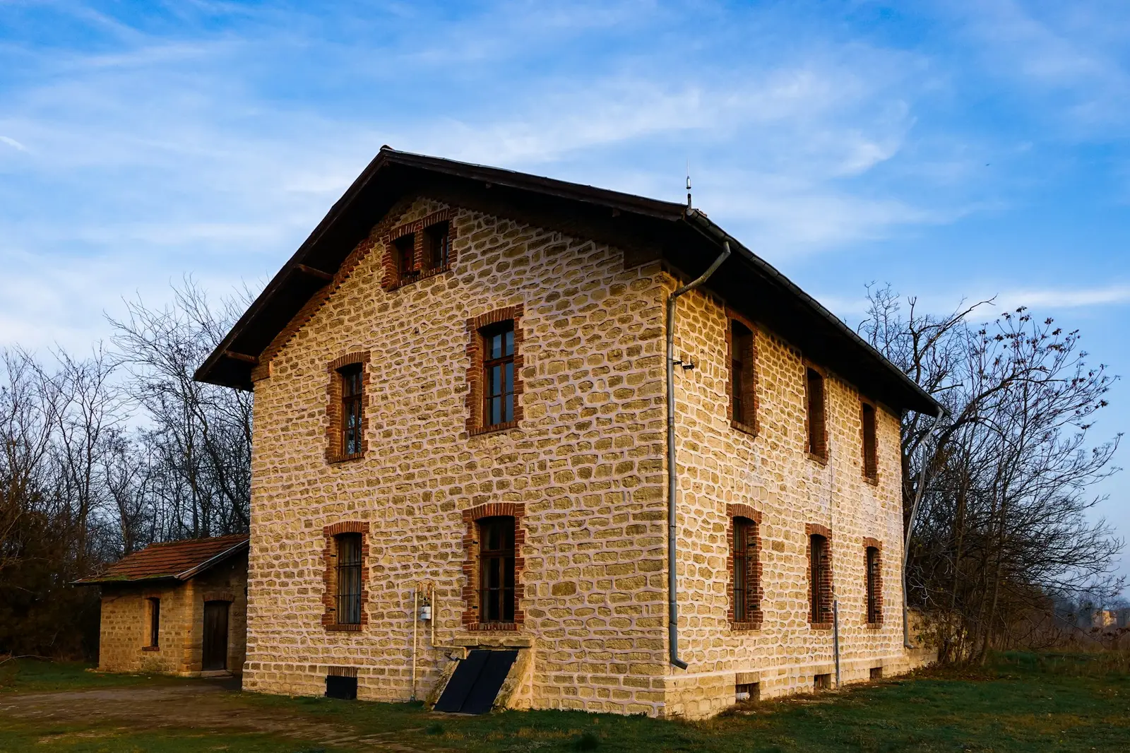 Two-story old cut-stone building under a blue sky