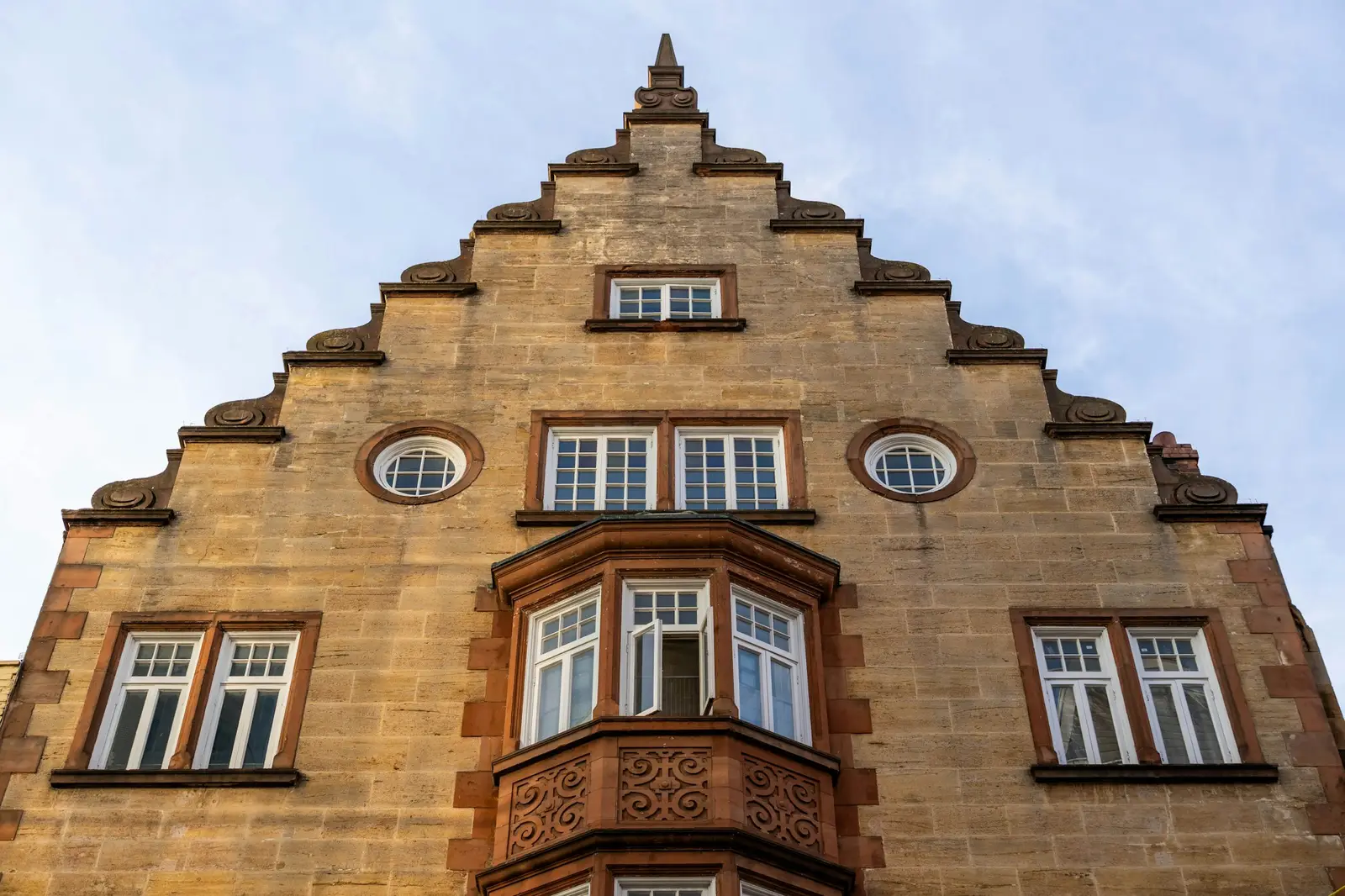 Historic stone-faced building with a stepped gable and a wood bay window