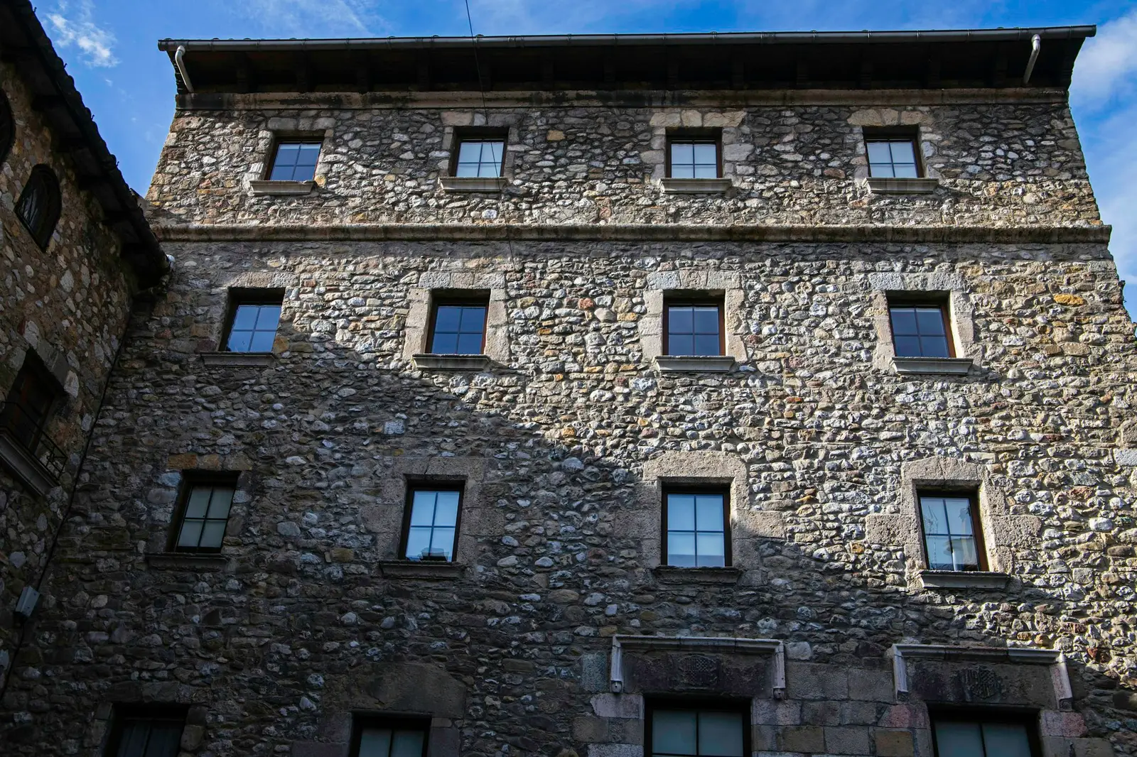 Tall rubble-stone building facade with small windows